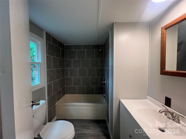 full bathroom featuring vanity, wood-type flooring, tiled shower / bath combo, and toilet