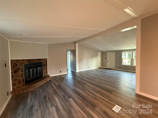 unfurnished living room with dark hardwood / wood-style flooring, lofted ceiling with beams, and a stone fireplace