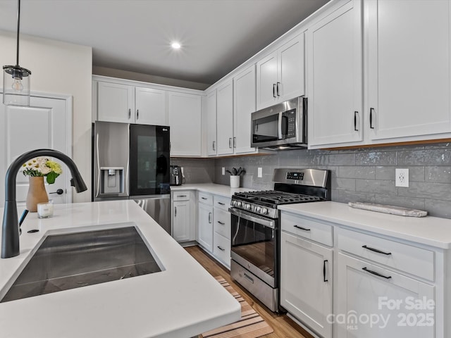 kitchen featuring appliances with stainless steel finishes, decorative light fixtures, sink, and white cabinets