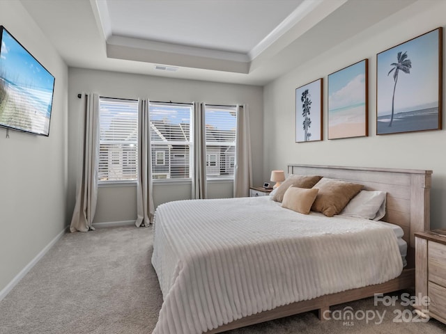 bedroom with a tray ceiling and light colored carpet