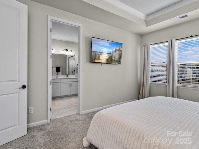 bedroom featuring light carpet, connected bathroom, and a tray ceiling