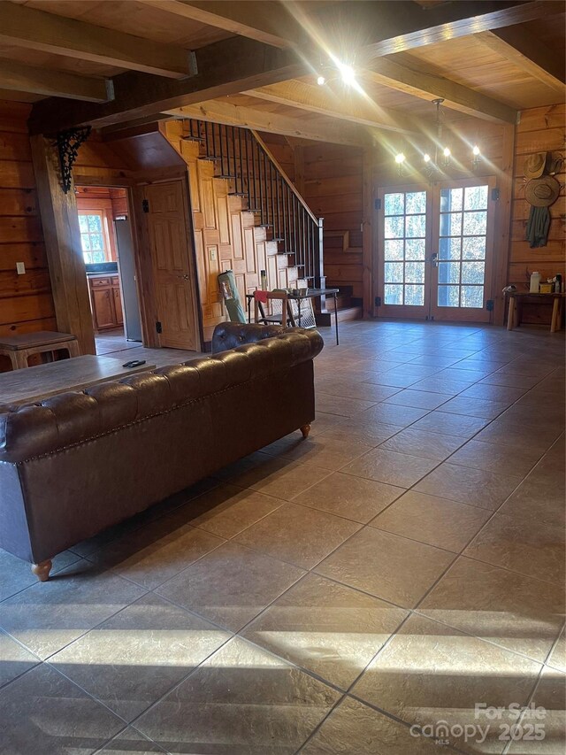 unfurnished living room featuring beamed ceiling and wooden walls