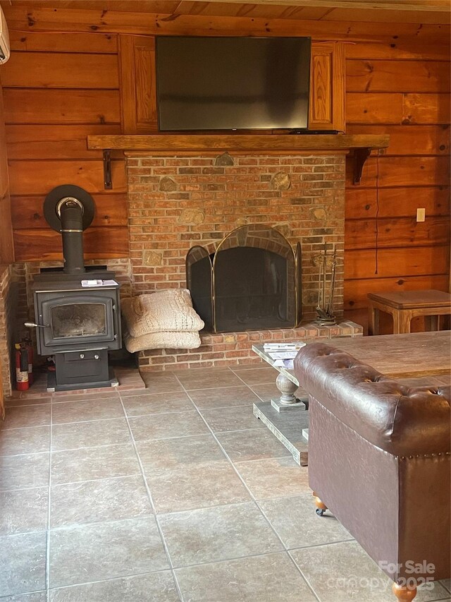 unfurnished living room with a wall mounted air conditioner, wooden walls, a brick fireplace, and a wood stove