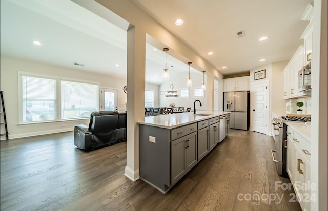 kitchen with appliances with stainless steel finishes, sink, dark hardwood / wood-style flooring, white cabinetry, and decorative light fixtures