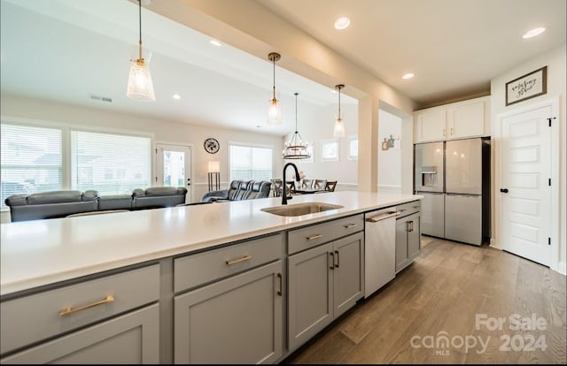 kitchen with wood-type flooring, appliances with stainless steel finishes, sink, pendant lighting, and gray cabinets