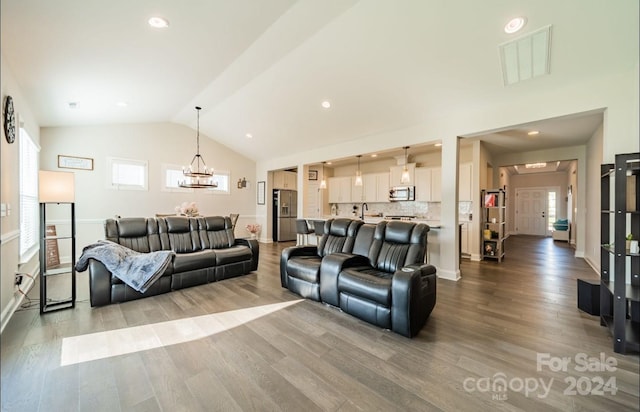 living room featuring an inviting chandelier, lofted ceiling, hardwood / wood-style floors, and sink