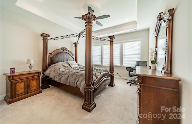 carpeted bedroom with a tray ceiling and ceiling fan