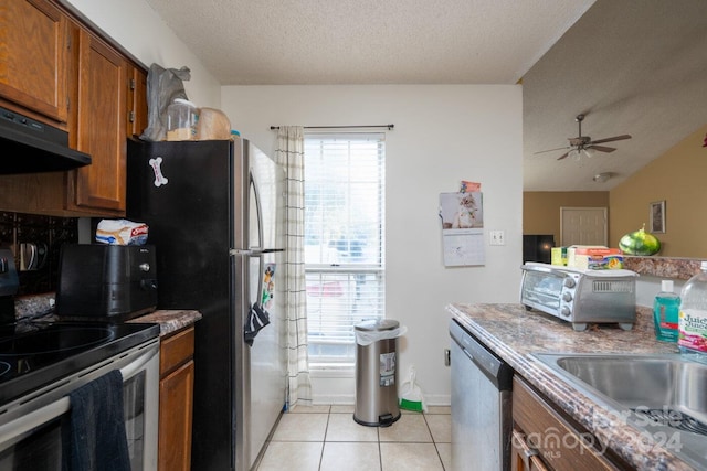 kitchen with a wealth of natural light, appliances with stainless steel finishes, a textured ceiling, and light tile patterned floors