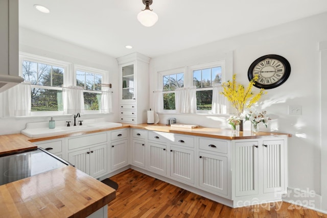 kitchen featuring dark wood-type flooring, plenty of natural light, white cabinets, and butcher block counters