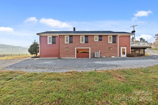 back of property with a garage, a deck, a lawn, and central air condition unit