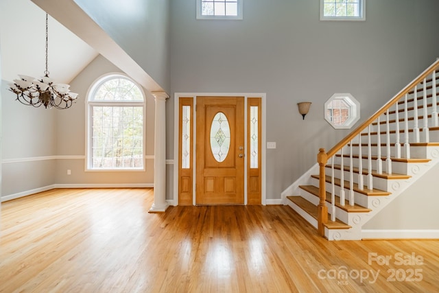 entrance foyer featuring a high ceiling, ornate columns, and wood-type flooring