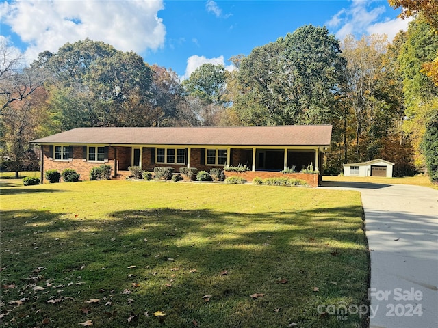 ranch-style home featuring covered porch, a front yard, an outdoor structure, and a garage