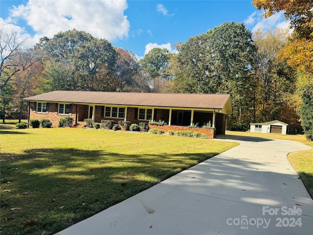 single story home with an outdoor structure and a front lawn