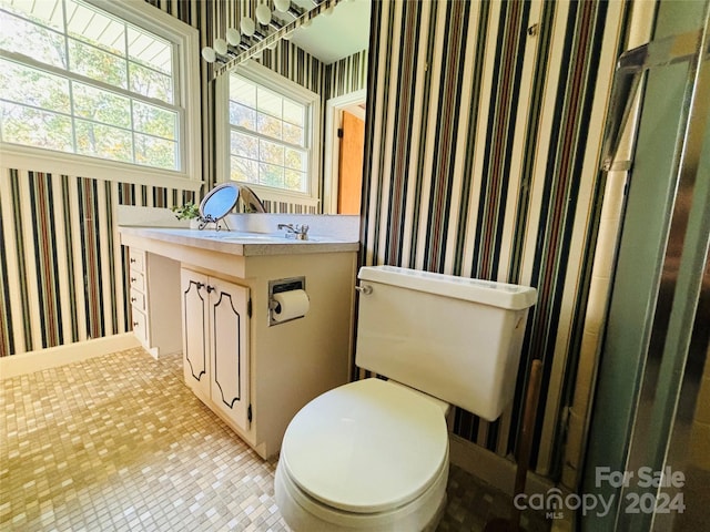 bathroom with toilet, vanity, and tile patterned flooring