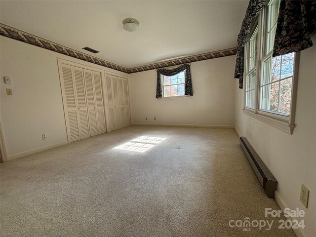 unfurnished bedroom featuring a baseboard heating unit and carpet floors