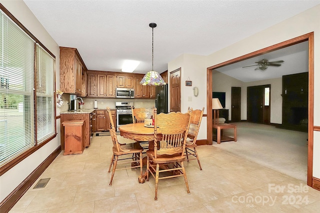 dining room with lofted ceiling, a textured ceiling, sink, ceiling fan, and light tile patterned flooring