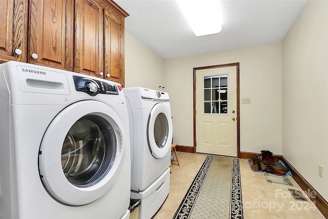 laundry room featuring a textured ceiling, washer and clothes dryer, cabinets, and light tile patterned floors