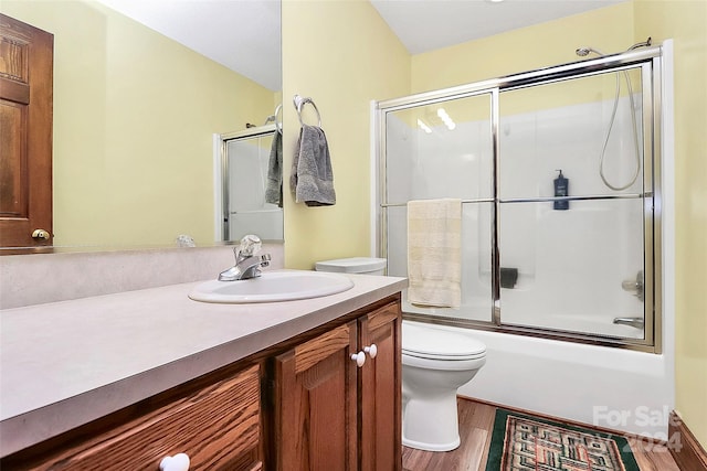 full bathroom with hardwood / wood-style flooring, enclosed tub / shower combo, vanity, and toilet