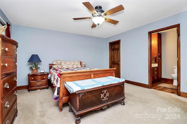 bedroom featuring connected bathroom, a textured ceiling, light carpet, and ceiling fan