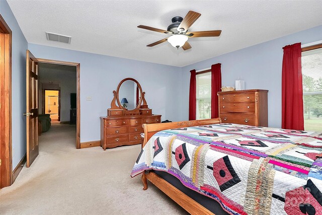 bedroom with a textured ceiling, light colored carpet, and ceiling fan