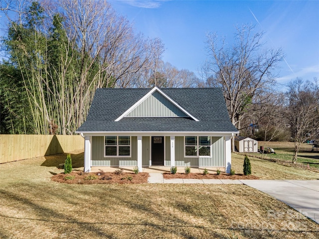 view of front of property featuring a porch, a storage unit, and a front yard