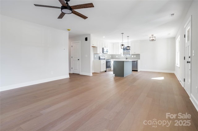 unfurnished living room with ceiling fan, sink, and light hardwood / wood-style flooring