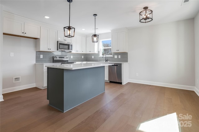 kitchen with stainless steel appliances, decorative light fixtures, a center island, and white cabinets