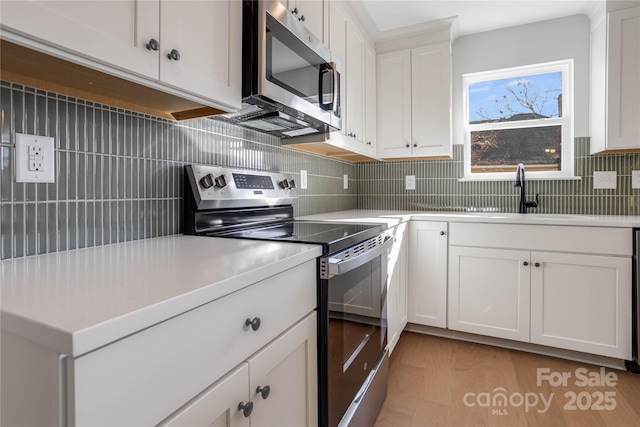 kitchen with appliances with stainless steel finishes, sink, and white cabinets