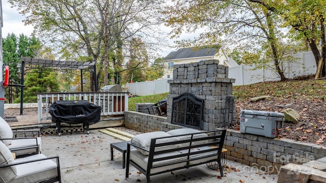 view of patio featuring an outdoor stone fireplace and a grill