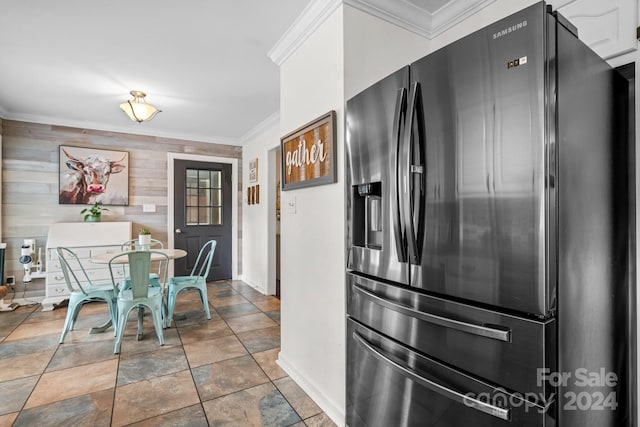 kitchen featuring white cabinets, crown molding, wood walls, and stainless steel fridge