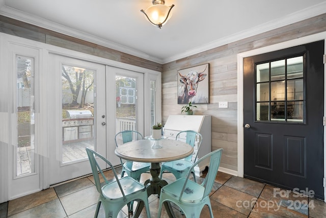 dining area featuring french doors, ornamental molding, and wooden walls