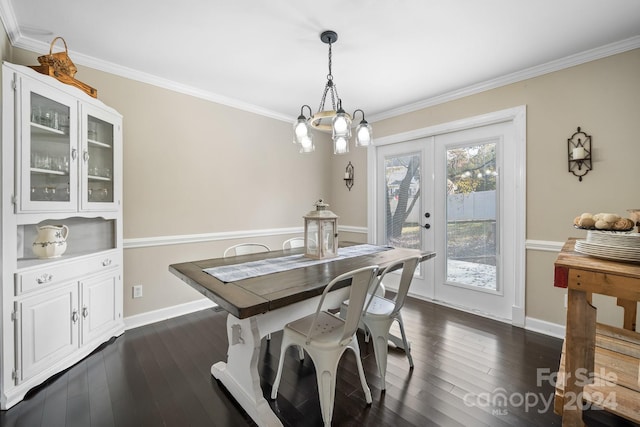 dining room with dark wood-type flooring, ornamental molding, a chandelier, and french doors