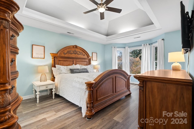 bedroom featuring hardwood / wood-style flooring, a tray ceiling, and ceiling fan