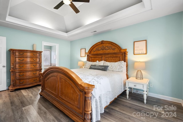 bedroom featuring a raised ceiling, dark hardwood / wood-style floors, and ceiling fan