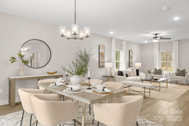 dining room with ceiling fan with notable chandelier and light hardwood / wood-style flooring