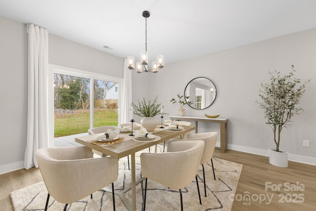 dining room with hardwood / wood-style floors and a notable chandelier