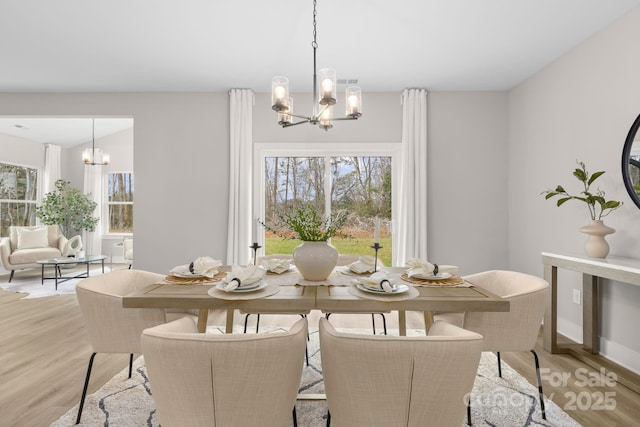 dining space with light wood-type flooring and a chandelier