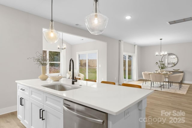 kitchen featuring sink, dishwasher, a notable chandelier, an island with sink, and white cabinets