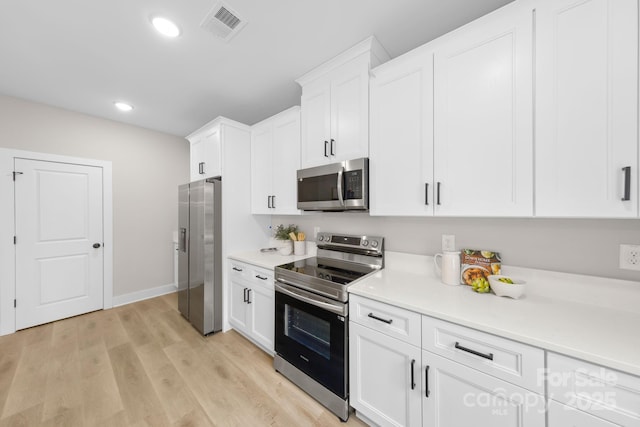 kitchen featuring appliances with stainless steel finishes, white cabinets, and light wood-type flooring