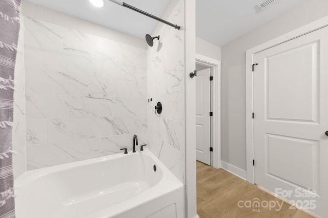 bathroom with hardwood / wood-style floors and tiled shower / bath combo