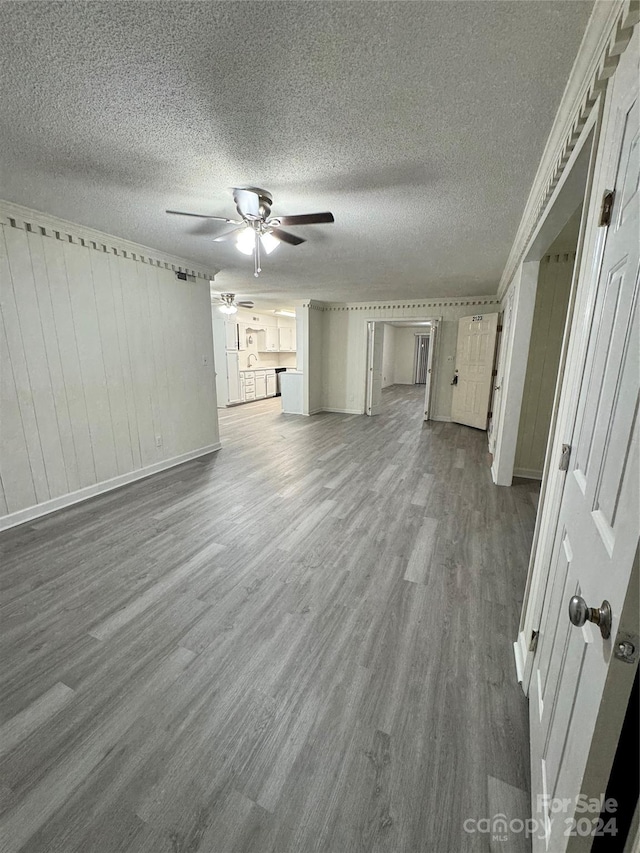 unfurnished living room with a textured ceiling, dark wood-type flooring, and ceiling fan