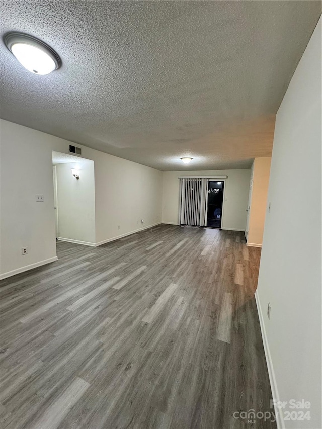 empty room with a textured ceiling and wood-type flooring