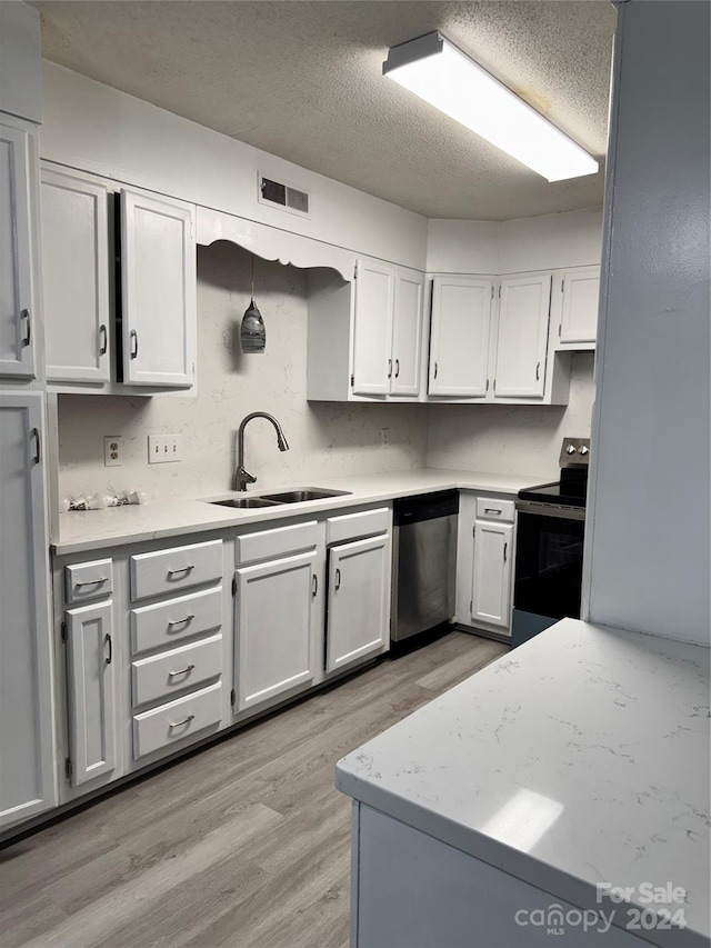 kitchen featuring hanging light fixtures, stainless steel appliances, sink, light wood-type flooring, and white cabinetry