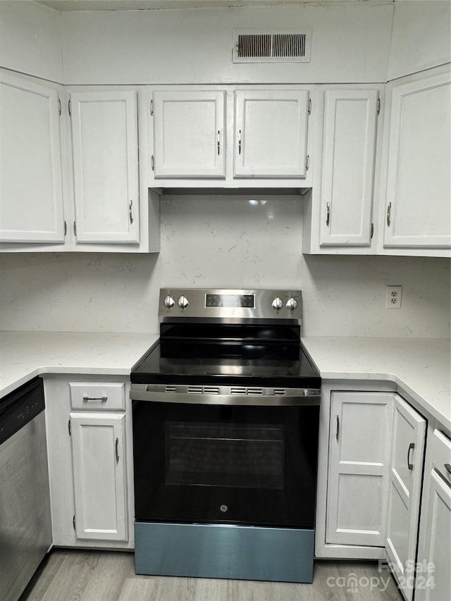 kitchen with light hardwood / wood-style floors, white cabinets, and stainless steel appliances