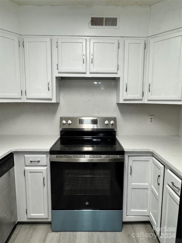 kitchen with appliances with stainless steel finishes, white cabinetry, and light hardwood / wood-style floors