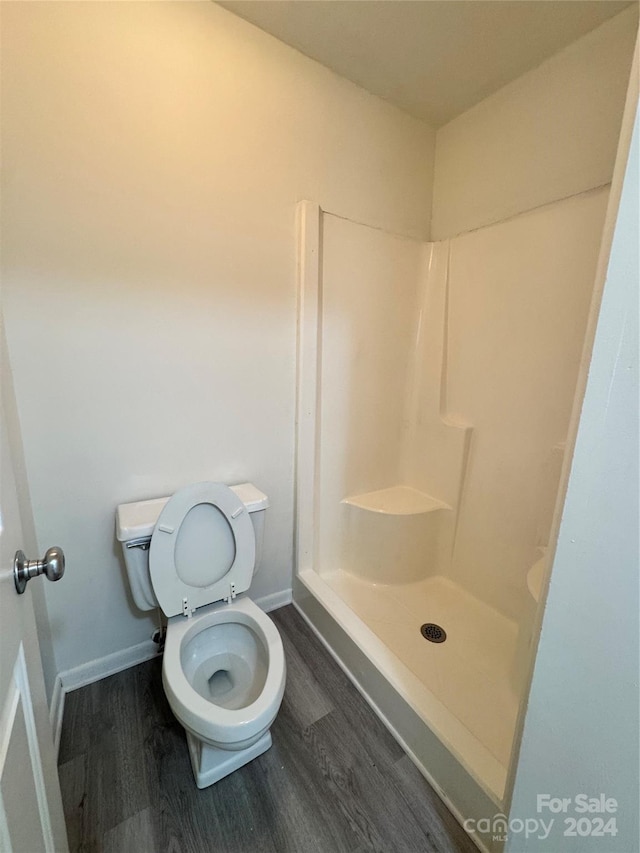 bathroom featuring hardwood / wood-style floors, toilet, and walk in shower