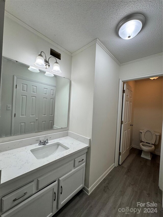 2123 Carriage Woods Ln, Kannapolis, NC 28081 - bathroom with wood finished floors, crown molding, vanity, a textured ceiling, and toilet
