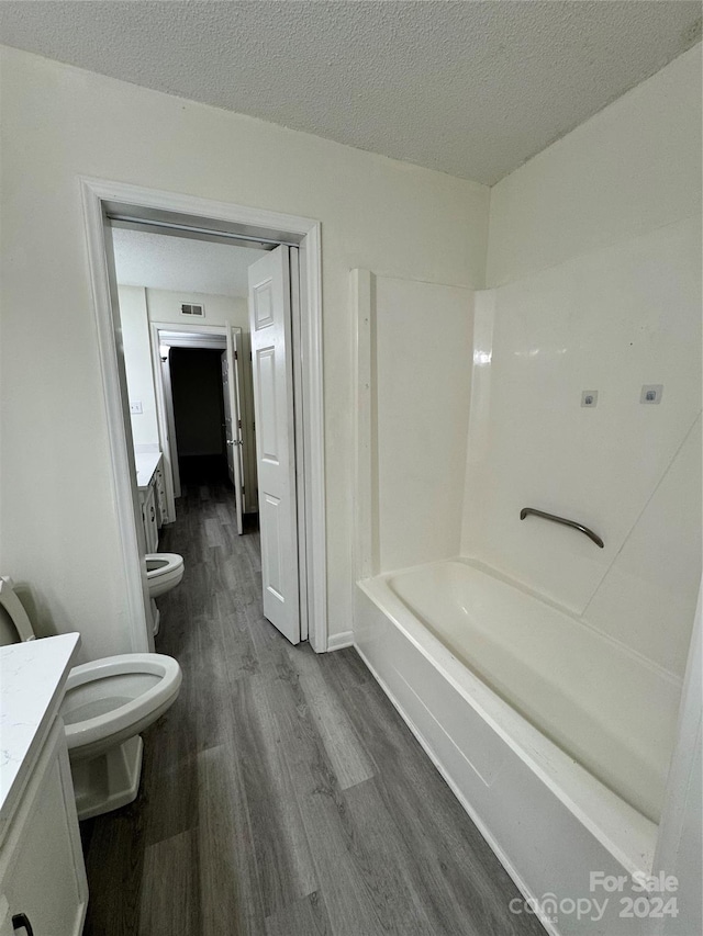 bathroom featuring vanity, hardwood / wood-style floors, a textured ceiling, and toilet