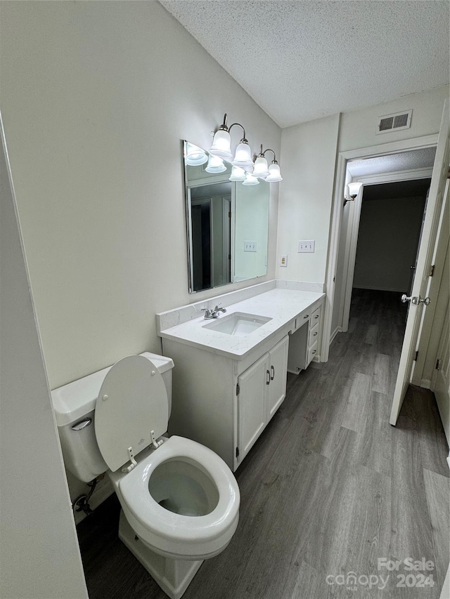 bathroom featuring vanity, a textured ceiling, hardwood / wood-style flooring, and toilet