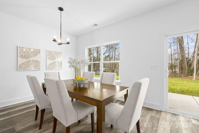 dining area with an inviting chandelier, plenty of natural light, and dark wood-type flooring